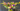 Bouquet of colorful flowers in a clear vase on a wooden table against a dark gray wall.