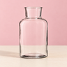 Alea clear glass vase with rounded shoulders and a narrow neck, on a neutral surface against a soft pink background